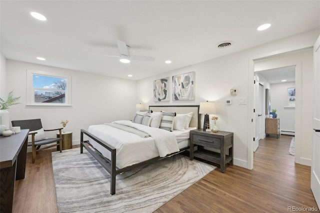 bedroom with recessed lighting, visible vents, baseboard heating, wood finished floors, and baseboards