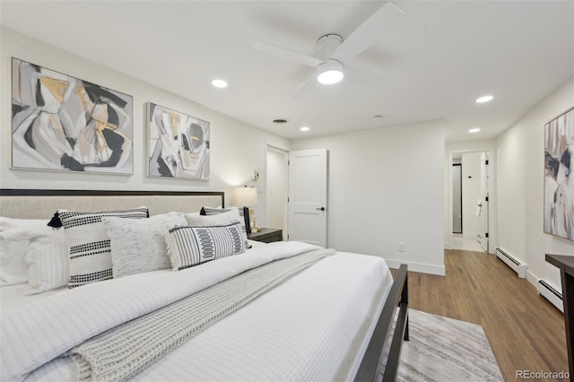 bedroom with a baseboard heating unit, wood finished floors, and recessed lighting