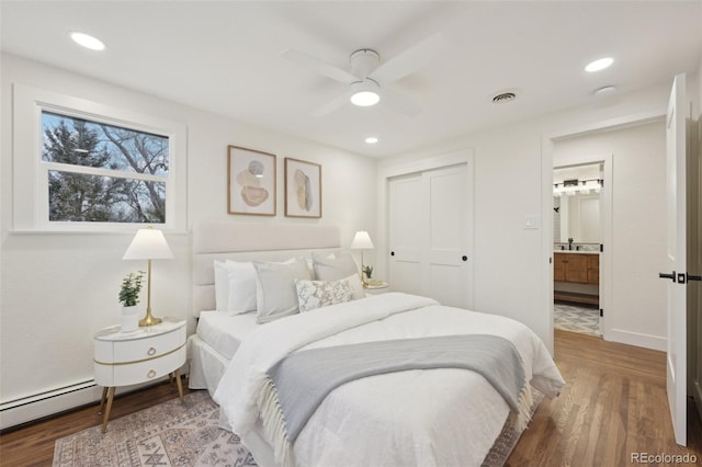 bedroom with a baseboard radiator, a closet, visible vents, and wood finished floors