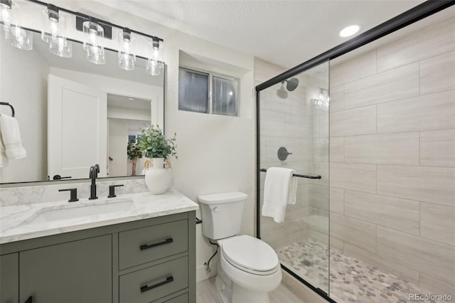 bathroom featuring vanity, a shower stall, and toilet