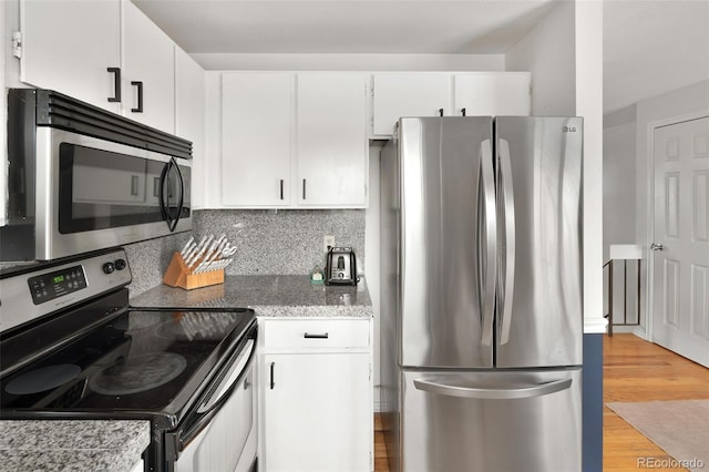 kitchen featuring white cabinetry, stainless steel appliances, light stone counters, tasteful backsplash, and light hardwood / wood-style floors