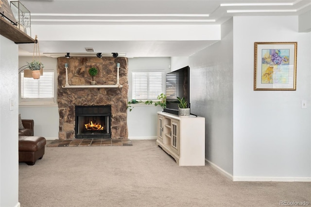 carpeted living room with a stone fireplace and a healthy amount of sunlight