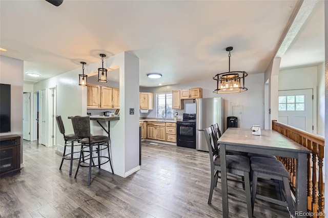 1166 W 98th Ave, Northglenn, CO 80260 - kitchen featuring light brown cabinetry, black range with electric cooktop, freestanding refrigerator, and plenty of natural light