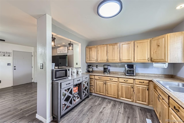 1166 W 98th Ave, Northglenn, CO 80260 - kitchen with stainless steel microwave, light brown cabinetry, wood finished floors, and light countertops