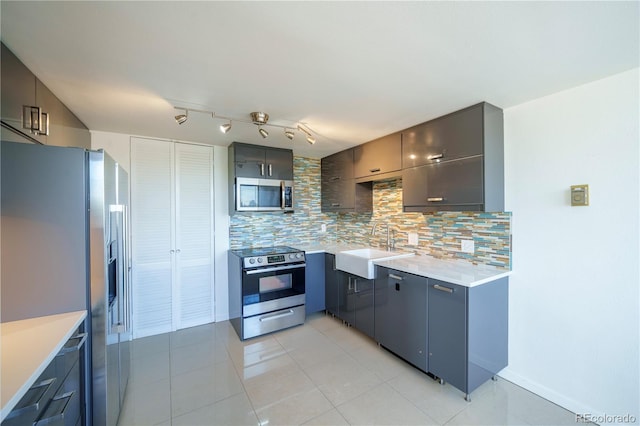 kitchen with sink, appliances with stainless steel finishes, rail lighting, and backsplash