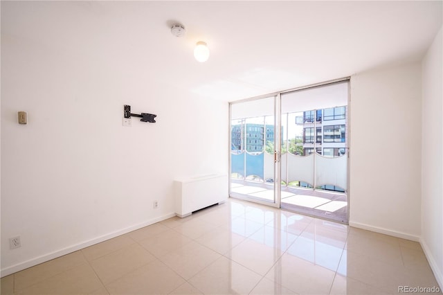 empty room with expansive windows and light tile patterned floors