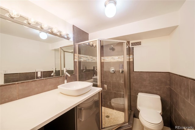 bathroom featuring toilet, an enclosed shower, and tile walls