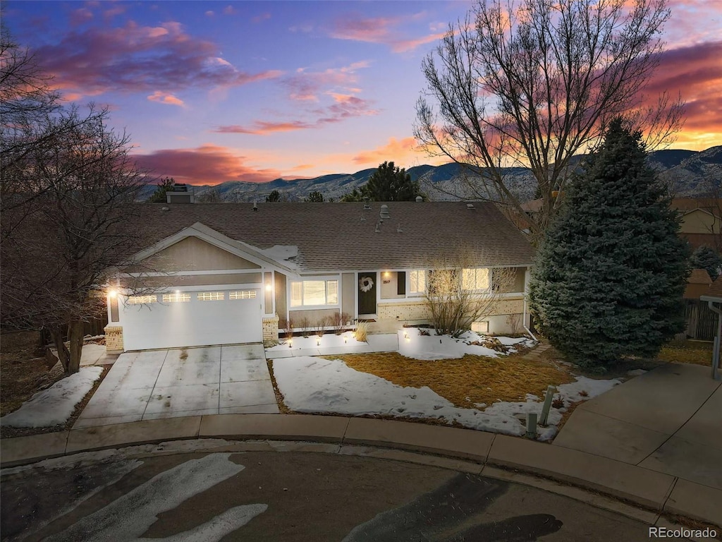 ranch-style home with an attached garage, a mountain view, and concrete driveway