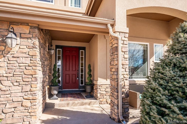 entrance to property featuring stone siding and stucco siding