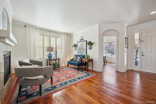 living area with ornamental molding, plenty of natural light, a fireplace, and wood finished floors