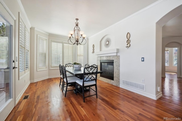 dining space with a notable chandelier, visible vents, arched walkways, and dark wood-style flooring