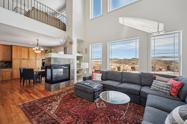 living room with a fireplace, wood finished floors, and a towering ceiling