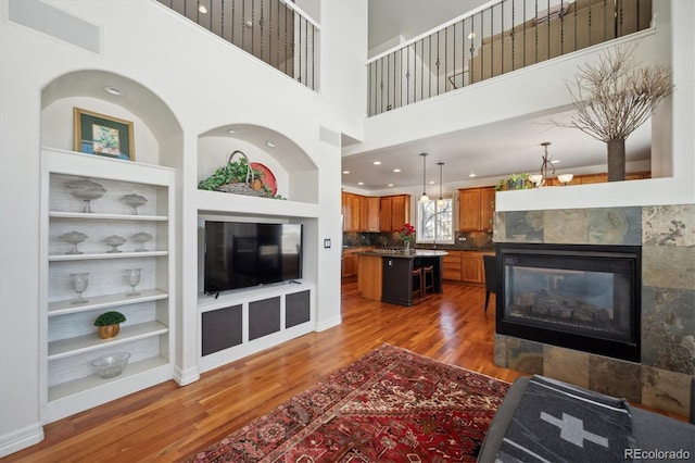 living room with built in shelves, a tile fireplace, baseboards, dark wood finished floors, and an inviting chandelier