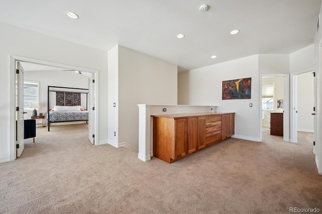 kitchen featuring light countertops, brown cabinetry, recessed lighting, and light colored carpet