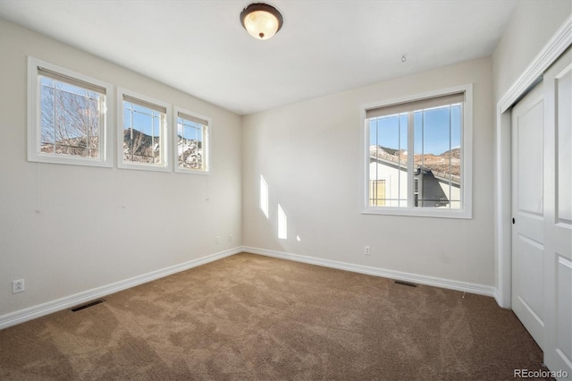 unfurnished bedroom with carpet floors, a closet, visible vents, and baseboards