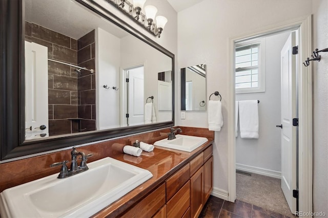 full bathroom with double vanity, baseboards, and a sink