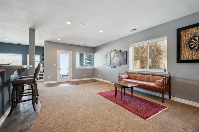 living room featuring baseboards, visible vents, dark colored carpet, and a textured ceiling