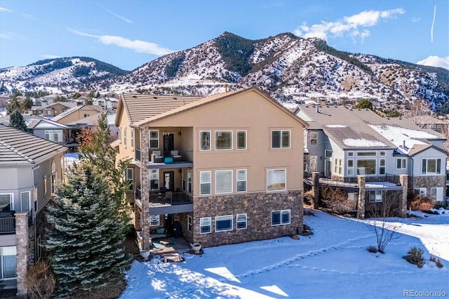 exterior space with stone siding, a mountain view, and stucco siding