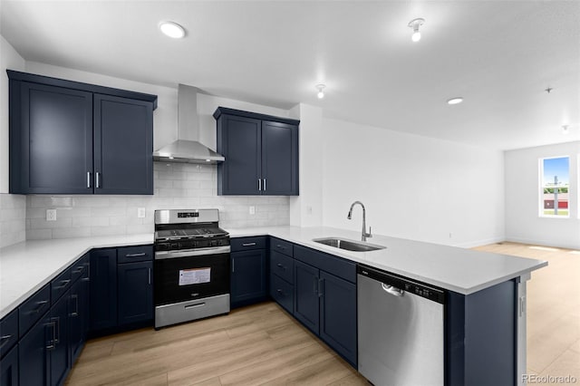 2740 W 68th Ave, Denver, CO 80221 - kitchen with stainless steel appliances, wall chimney range hood, a peninsula, light countertops, and light wood-style flooring