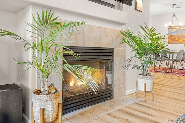 room details featuring a tiled fireplace, wood finished floors, a chandelier, and visible vents