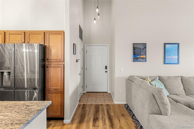 foyer entrance with a high ceiling, visible vents, baseboards, and light wood-type flooring