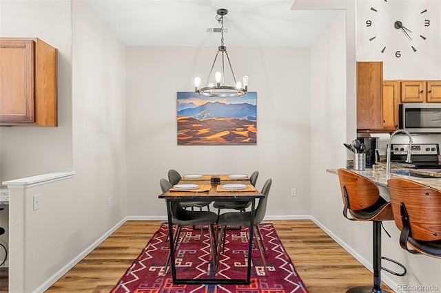 dining room featuring an inviting chandelier, baseboards, and light wood-style flooring