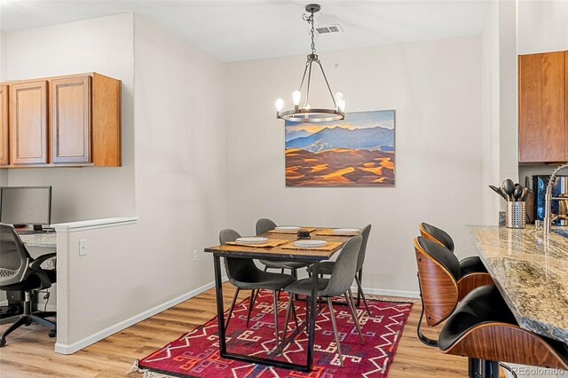 dining room with an inviting chandelier, light wood finished floors, baseboards, and visible vents