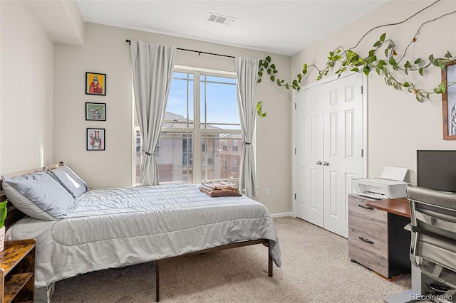 bedroom with a closet, baseboards, light colored carpet, and visible vents