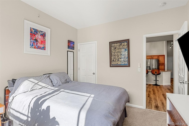 bedroom featuring baseboards, carpet, and stainless steel refrigerator with ice dispenser