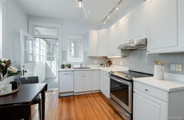 kitchen with under cabinet range hood, white dishwasher, stainless steel range with electric cooktop, and white cabinets