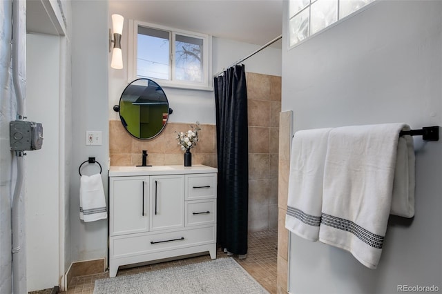full bathroom featuring a tile shower, vanity, and decorative backsplash