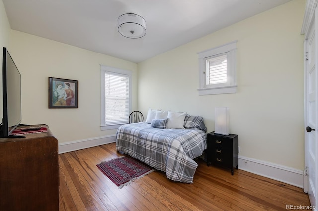 bedroom with wood-type flooring, baseboards, and multiple windows