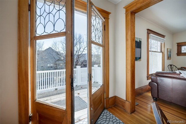 doorway to outside featuring light wood-style floors, ornamental molding, and french doors