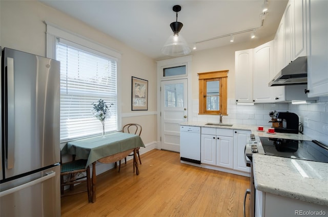 kitchen featuring stainless steel appliances, under cabinet range hood, a sink, tasteful backsplash, and white cabinets