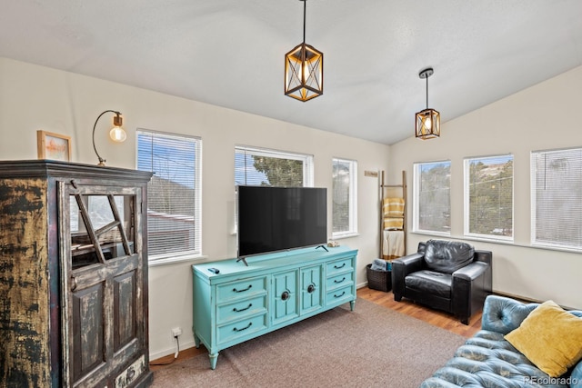 living room featuring lofted ceiling, baseboards, and light wood finished floors
