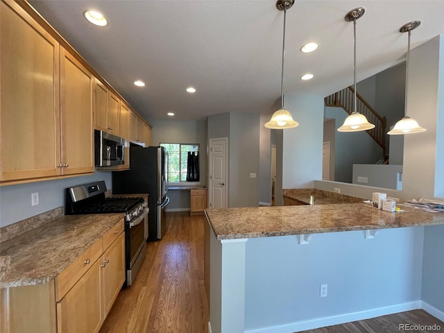 kitchen with stainless steel appliances, dark wood-type flooring, kitchen peninsula, pendant lighting, and light brown cabinetry