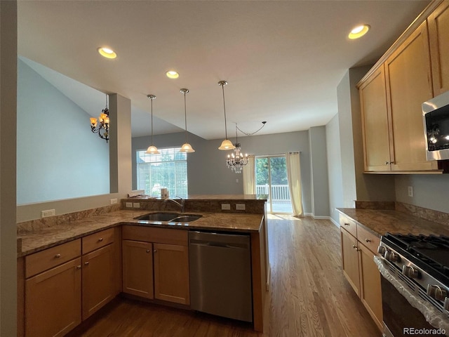 kitchen featuring kitchen peninsula, appliances with stainless steel finishes, sink, a notable chandelier, and hanging light fixtures