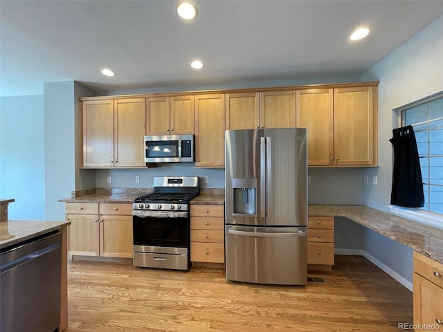 kitchen with stone counters, built in desk, light wood-type flooring, light brown cabinetry, and appliances with stainless steel finishes