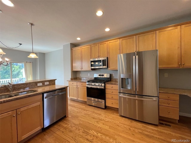 kitchen with appliances with stainless steel finishes, sink, an inviting chandelier, light hardwood / wood-style floors, and hanging light fixtures