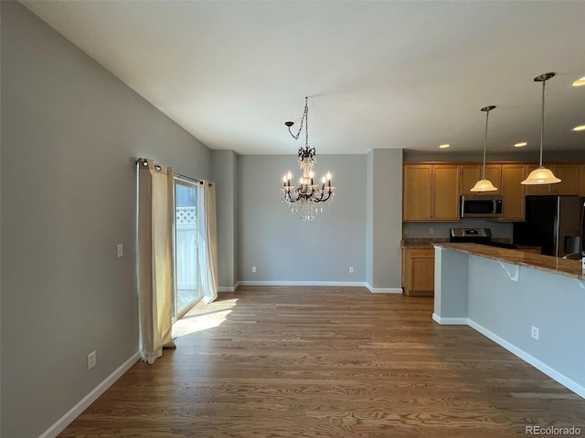 kitchen featuring hanging light fixtures, dark hardwood / wood-style floors, light brown cabinetry, appliances with stainless steel finishes, and a chandelier