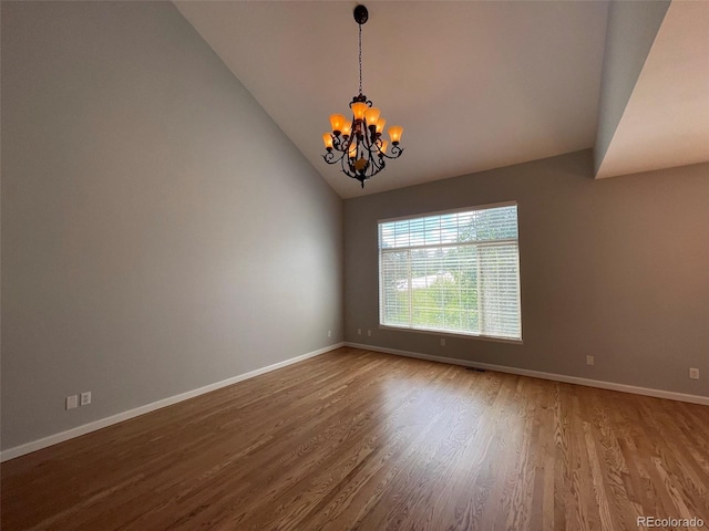 spare room with hardwood / wood-style floors, a notable chandelier, and lofted ceiling