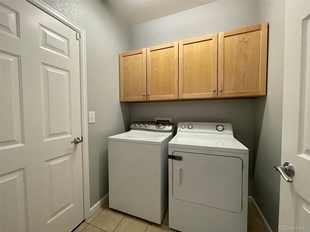 laundry room featuring separate washer and dryer, light tile patterned floors, and cabinets