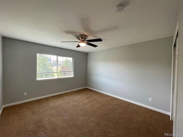 unfurnished room with dark colored carpet and ceiling fan