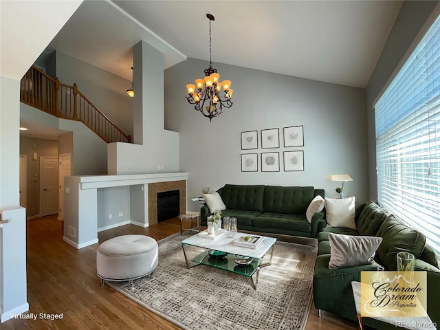 living room with hardwood / wood-style floors, a chandelier, lofted ceiling, and a tiled fireplace