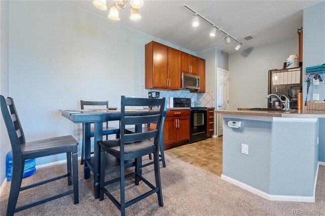 2682 S Cathay Way Unit 307, Aurora, CO 80013 - kitchen with black range with electric stovetop, stainless steel microwave, a sink, decorative backsplash, and light colored carpet
