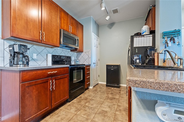2682 S Cathay Way Unit 307, Aurora, CO 80013 - kitchen featuring black electric range, stainless steel microwave, backsplash, a sink, and rail lighting