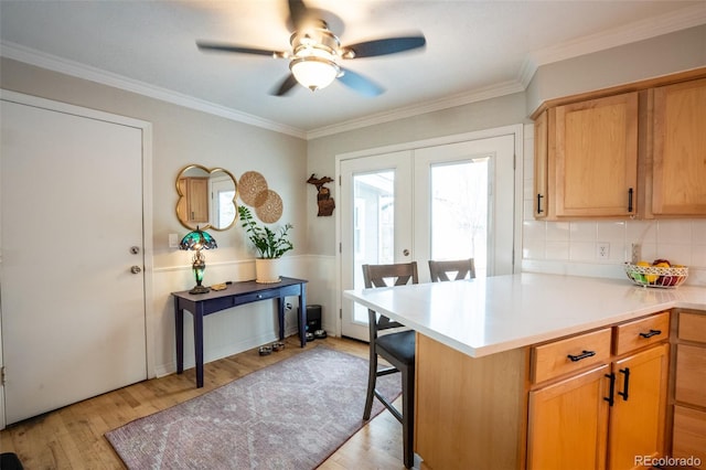 kitchen with light hardwood / wood-style floors, kitchen peninsula, a breakfast bar area, and french doors