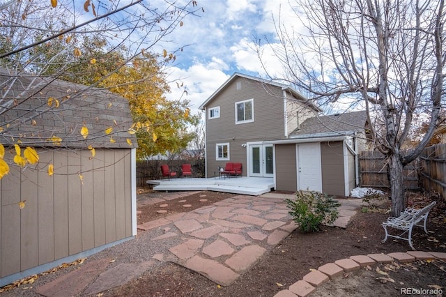 back of house with french doors, a patio, an outdoor structure, and a deck