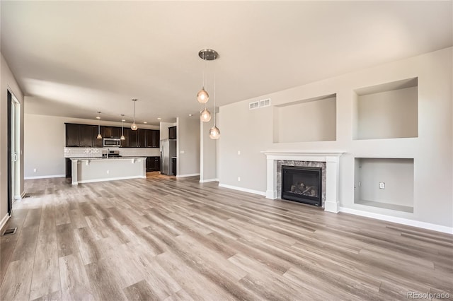 6612 S Muscadine Ct, Aurora, CO 80016 - unfurnished living room with baseboards, light wood finished floors, a fireplace, and recessed lighting