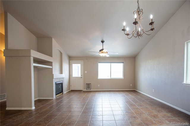 unfurnished living room with vaulted ceiling, tile patterned flooring, a tiled fireplace, and ceiling fan with notable chandelier